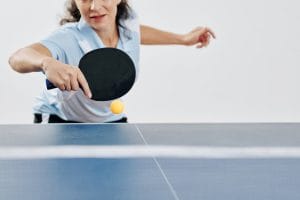 An image of a Professional female table tennis player hitting a ping-pong ball.