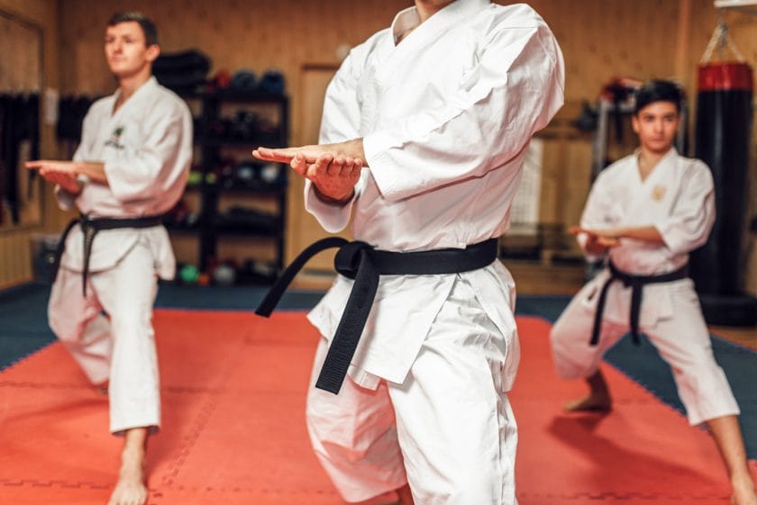 An image of Martial arts karate master and his disciples in white uniform and black belts, fight training in action, workout in gym.