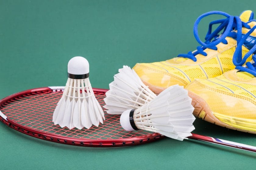 An image of badminton shuttlecocks with a racket and a pair of sport shoes.