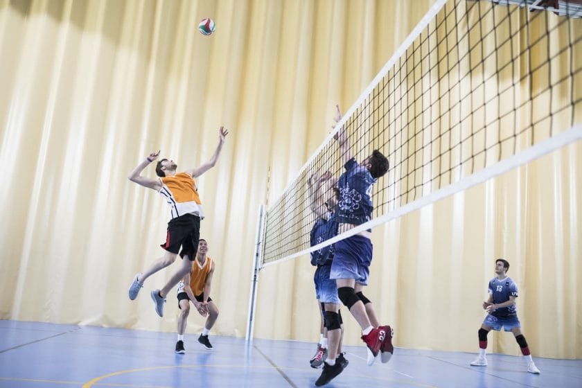 An image of a man jumping during a volleyball match against the opponent team.