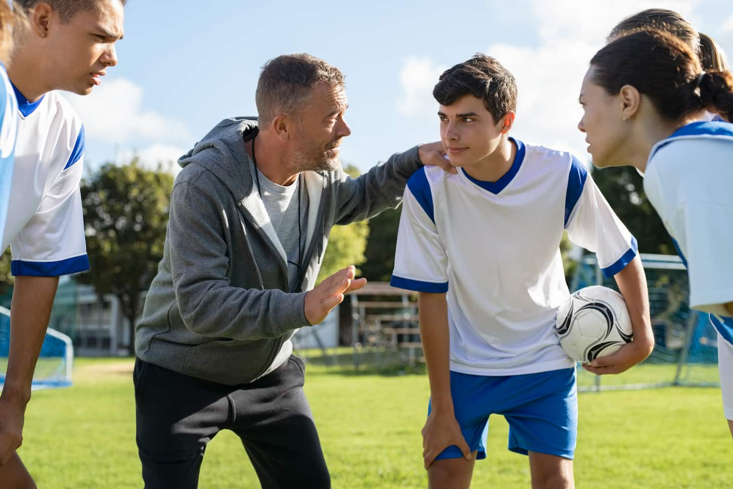 An image of Young soccer players standing together united and listening coach motivational speech.