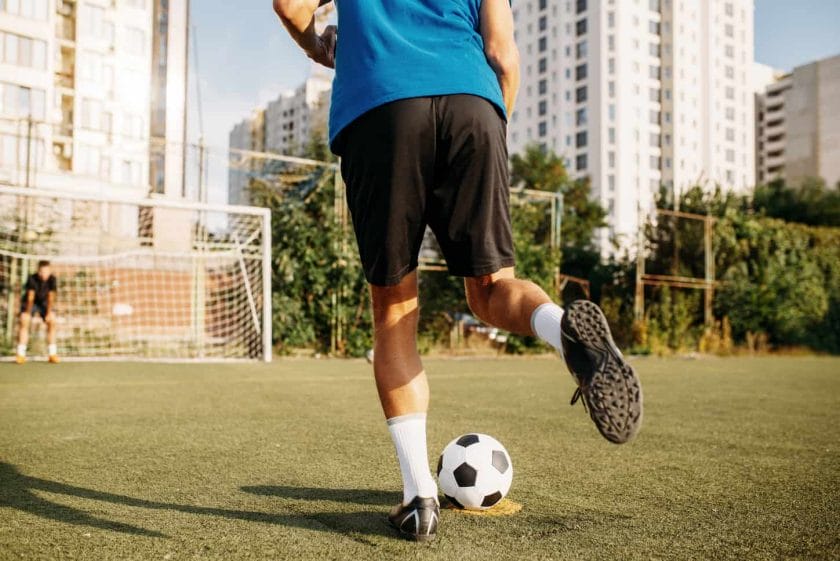 An image of a Male soccer player hits the ball on the soccer field.