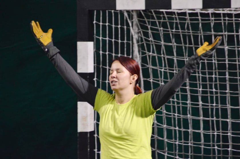 An image of a female goalkeeper in uniform and gloves during a handball match.