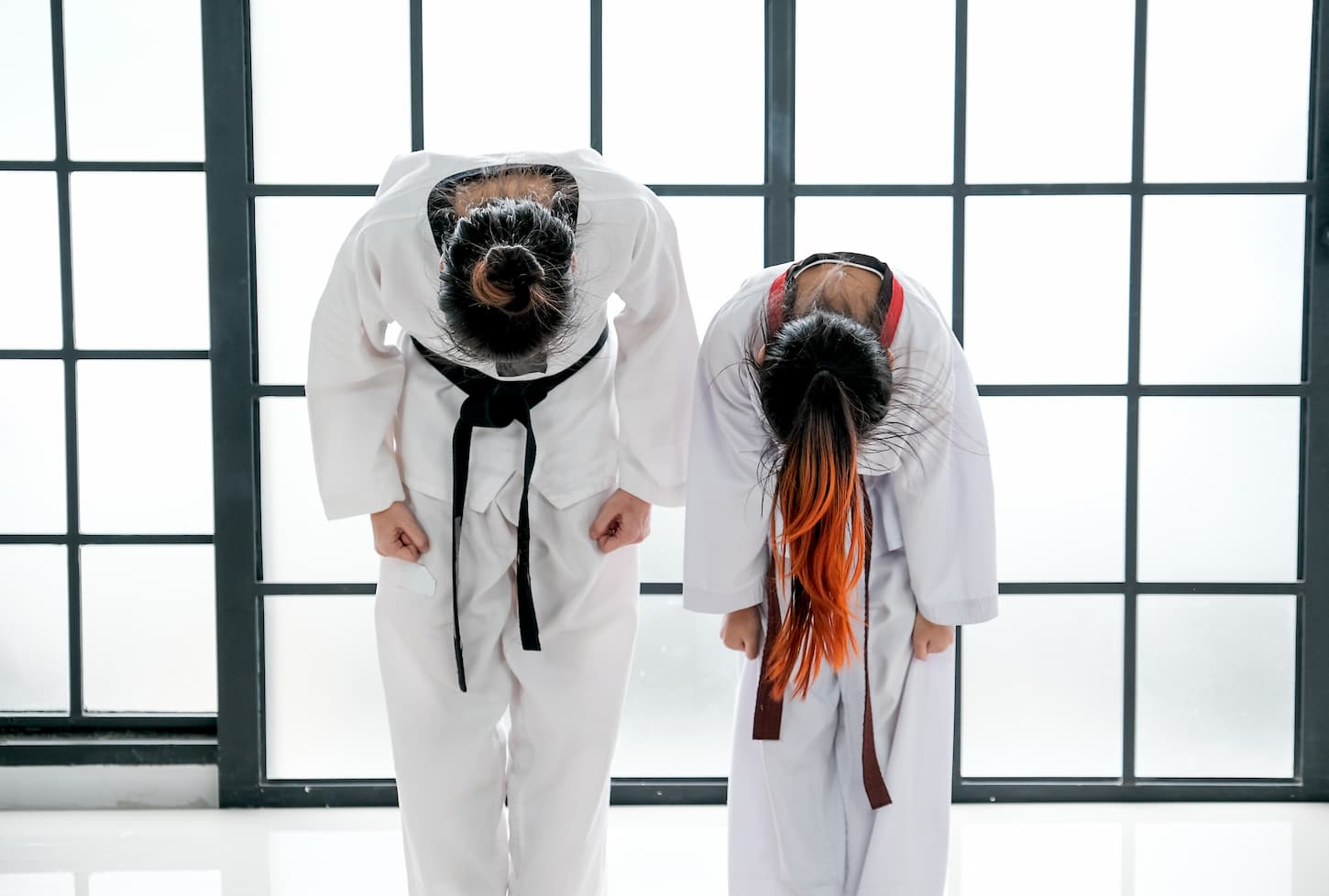 An image of an Asian Taekwondo teacher and student standing and bowing for saluting posture in general action of Taekwondo sport.