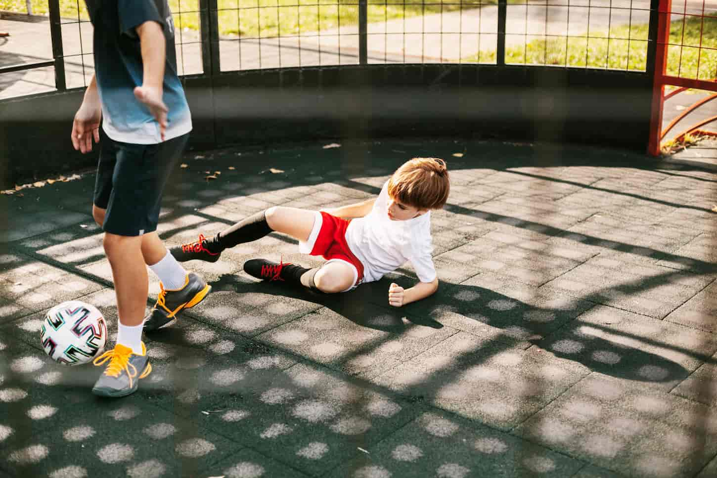 An image of Boys playing soccer on the freestyle soccer field. The boys fight for the ball in the game. Sports, games, competitions, football freestyle.