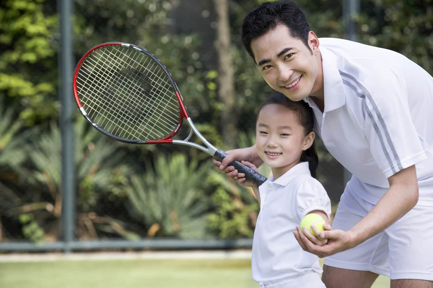 An image of a father and daughter on the tennis court.