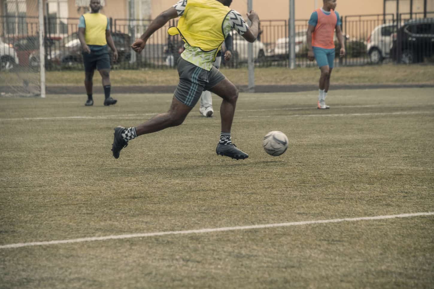 An image of a Football player or soccer player running fast and kicking a soccer ball in a stadium during a match.