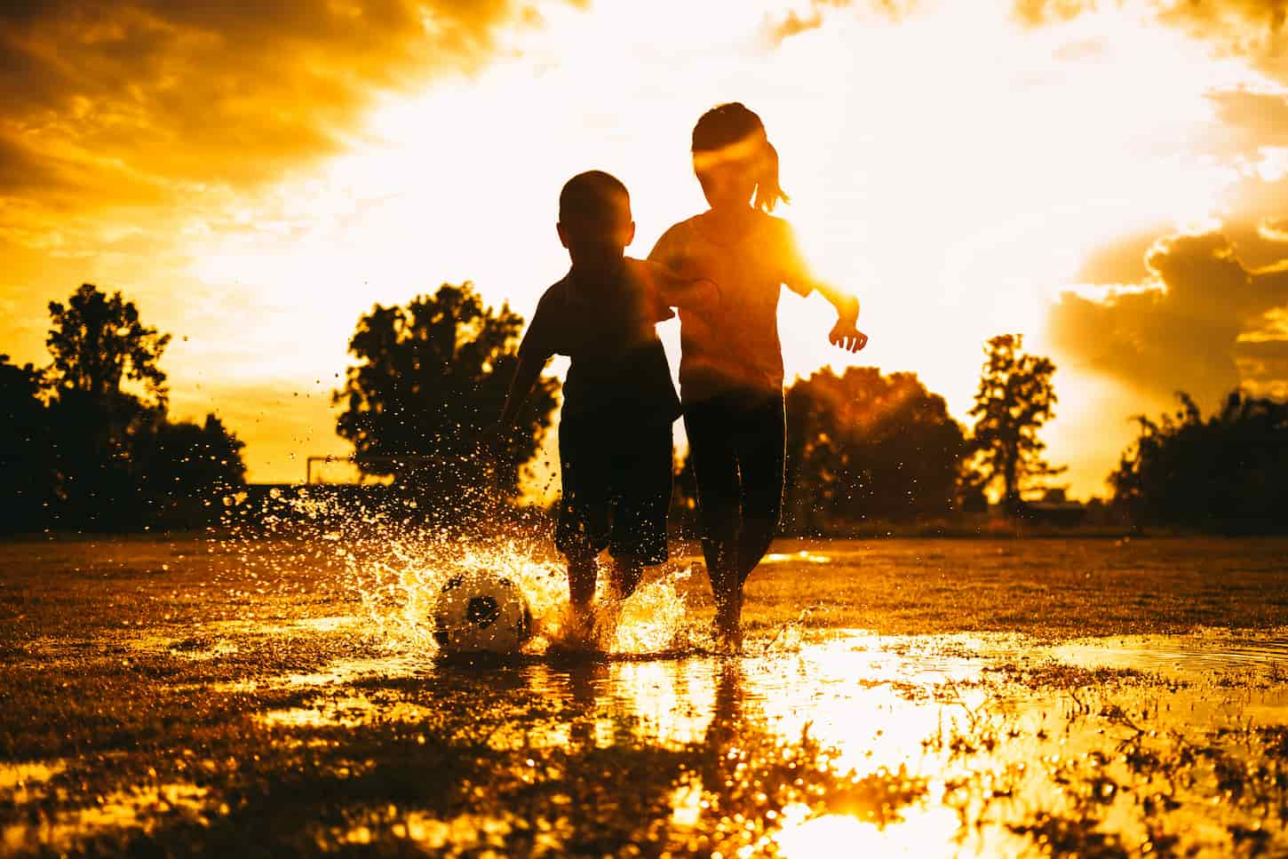 An image of Kids playing soccer football on the wet field after the rain.