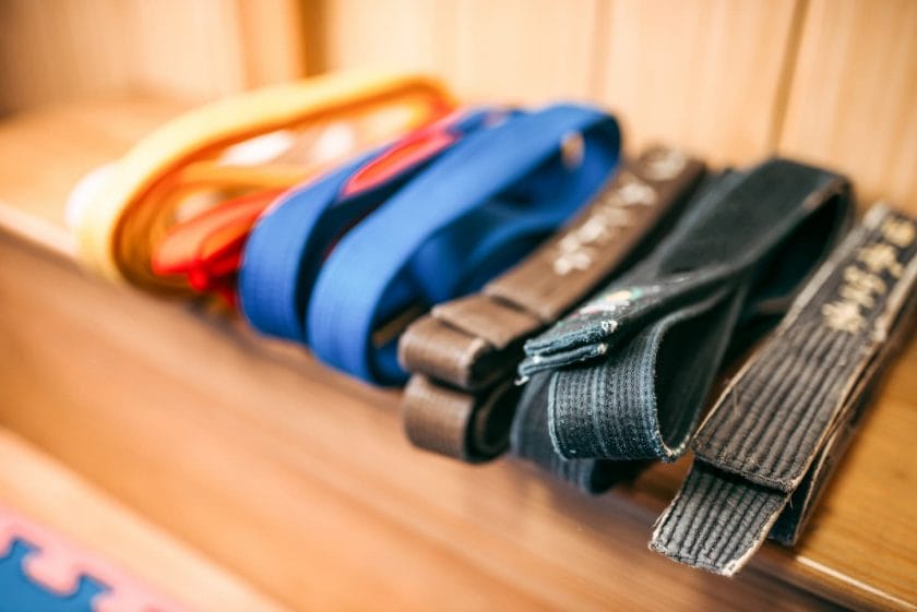 An image of brown, orange, blue, and black belts on the shelf.