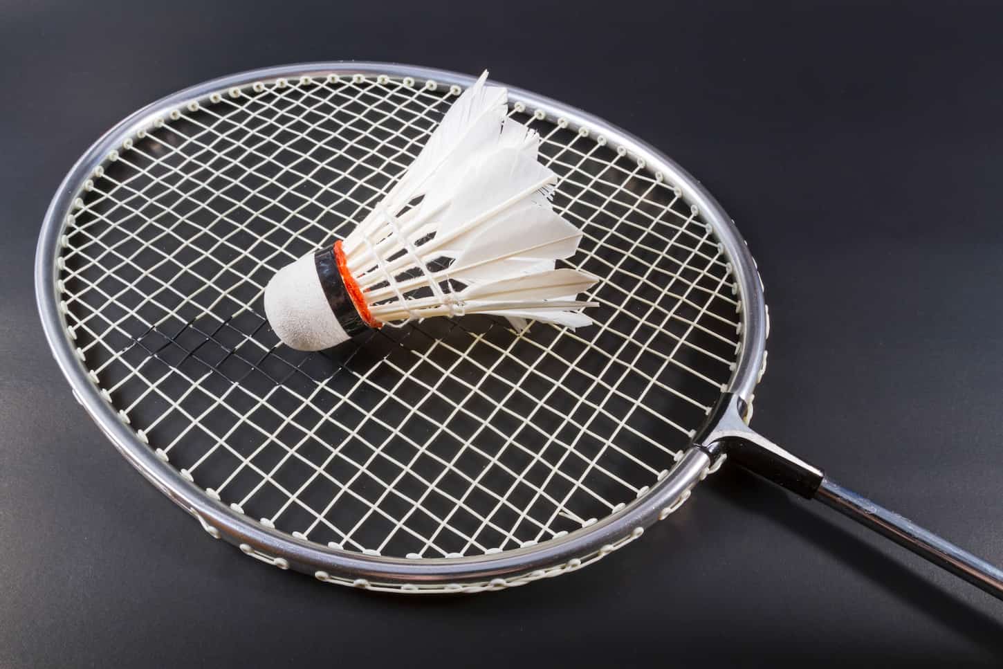 An image of a Shuttlecock and a badminton racket on dark background.