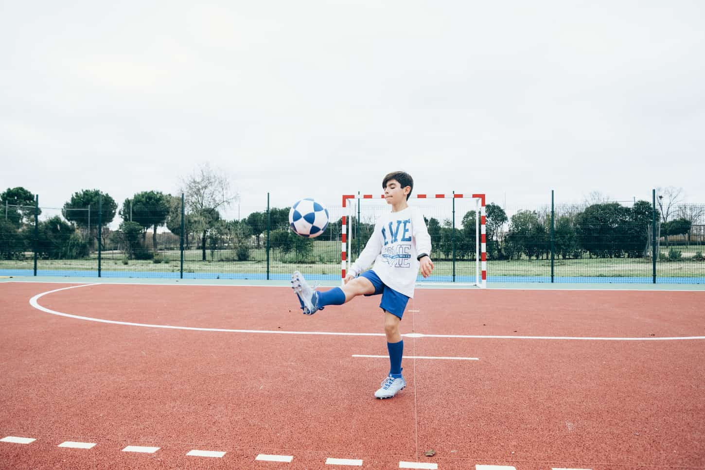 An image of a Soccer player boy hitting the ball.