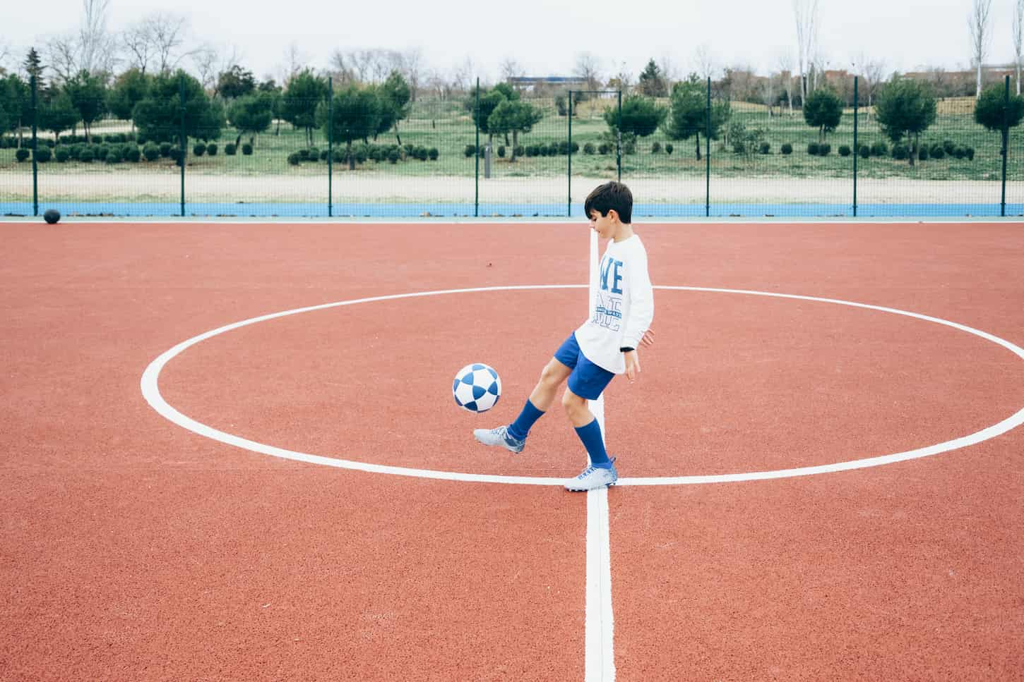 An image of a Soccer player boy hitting the ball.