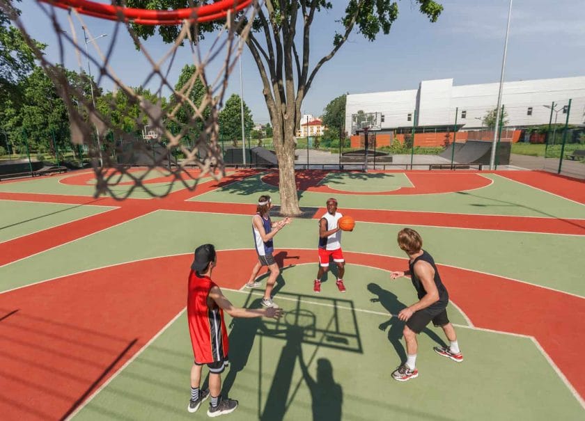 An image of a multiracial sports team playing a basketball game at an outdoor arena.