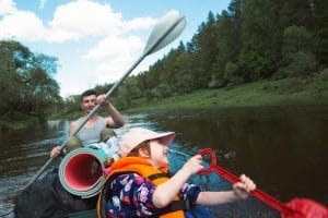 An image of a Family kayak trip. Father and daughter rowing boat on the river, a water hike, a summer adventure.