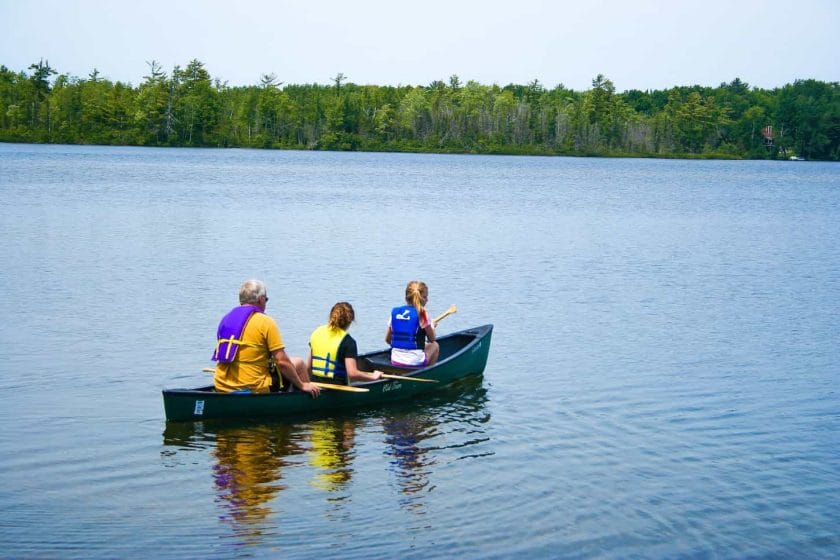 An image of Grandpa and granddaughters kayaking on the lake.
