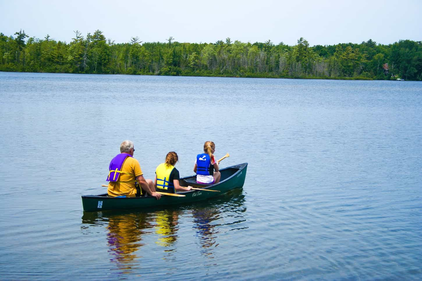 An image of Grandpa and granddaughters kayaking on the lake.