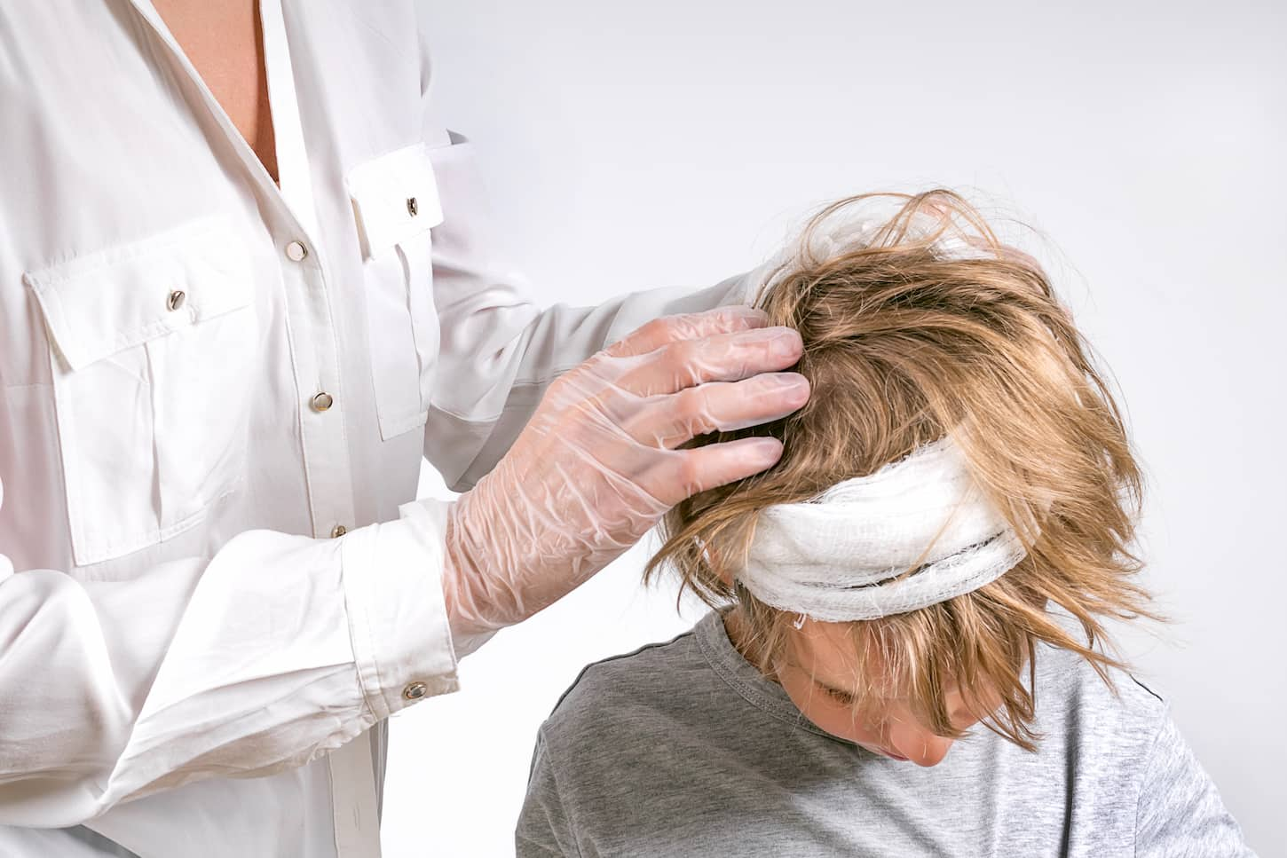 An image of a Doctor providing medical care to a young boy with head injury trauma.