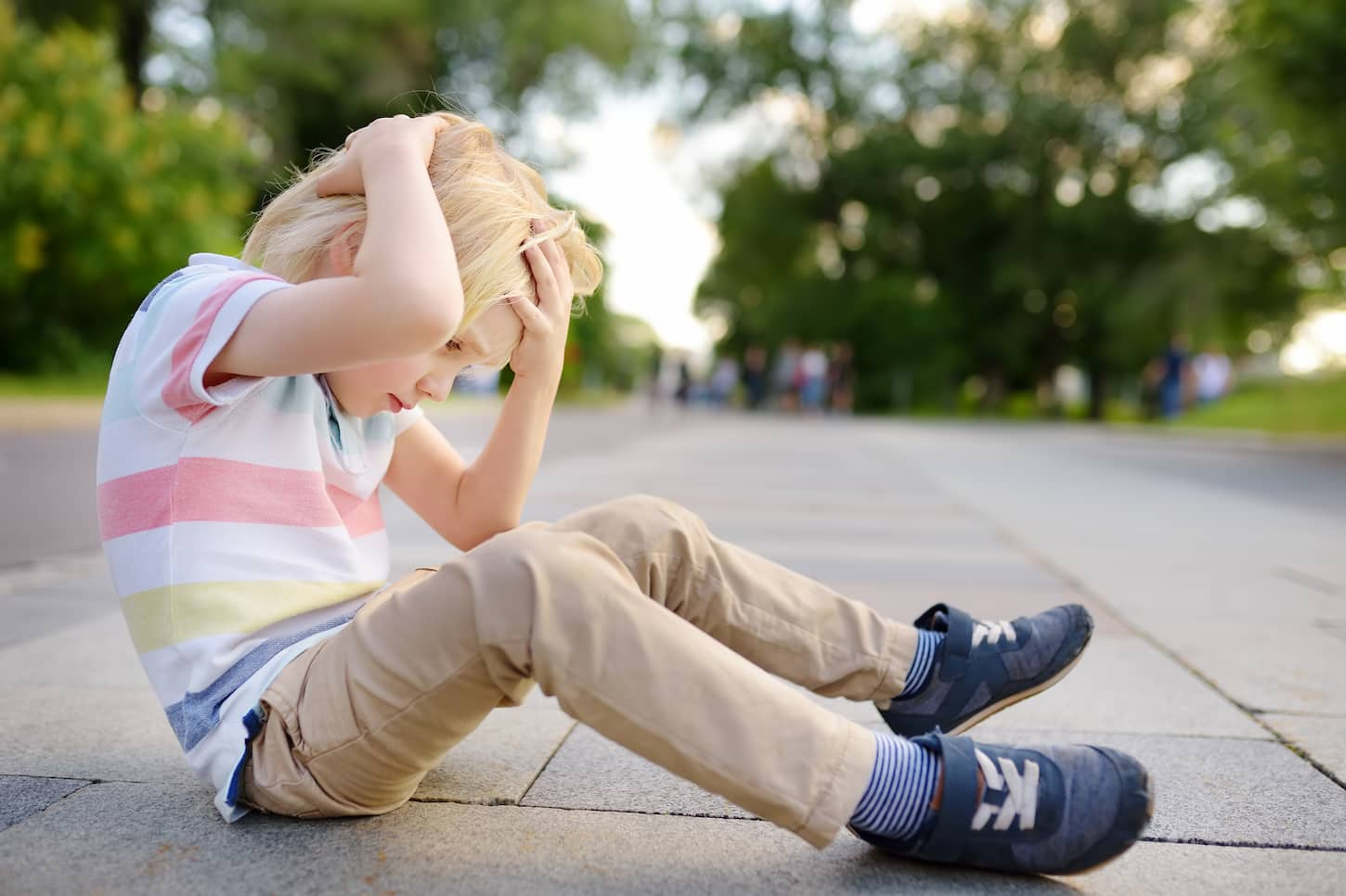 An image of a little boy who fell and got hurt on the street.