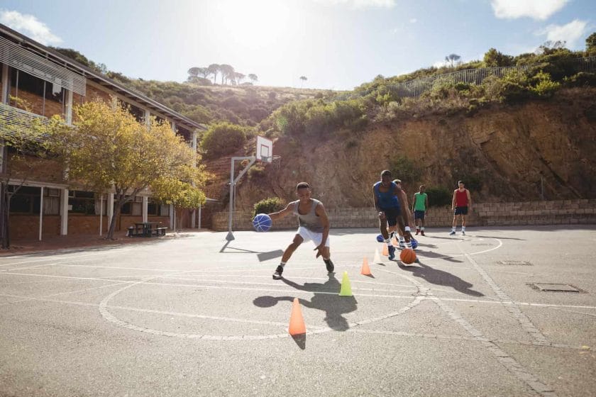 An image of Basketball players practicing dribbling drills.