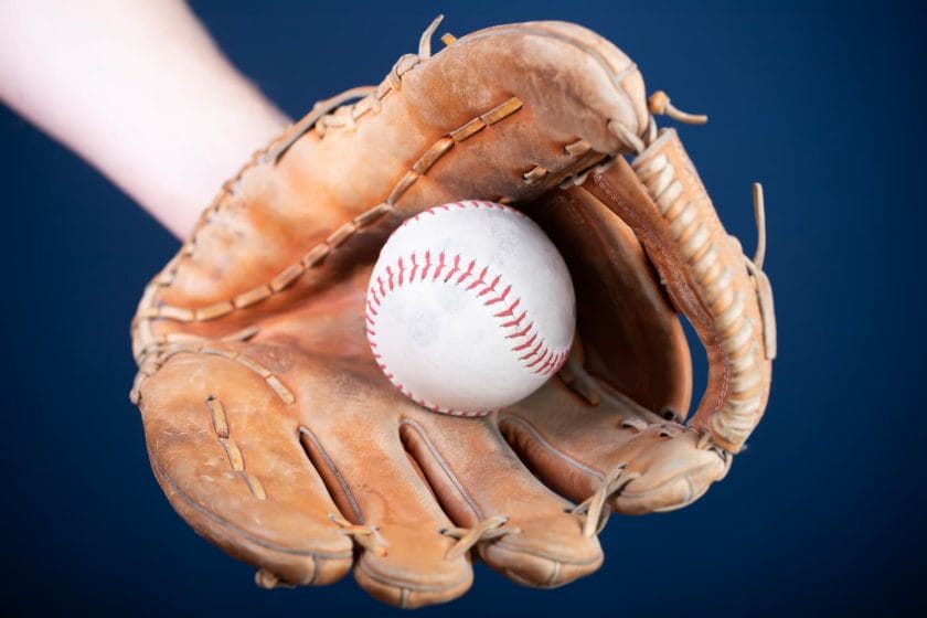 An image of an old used baseball and baseball glove.