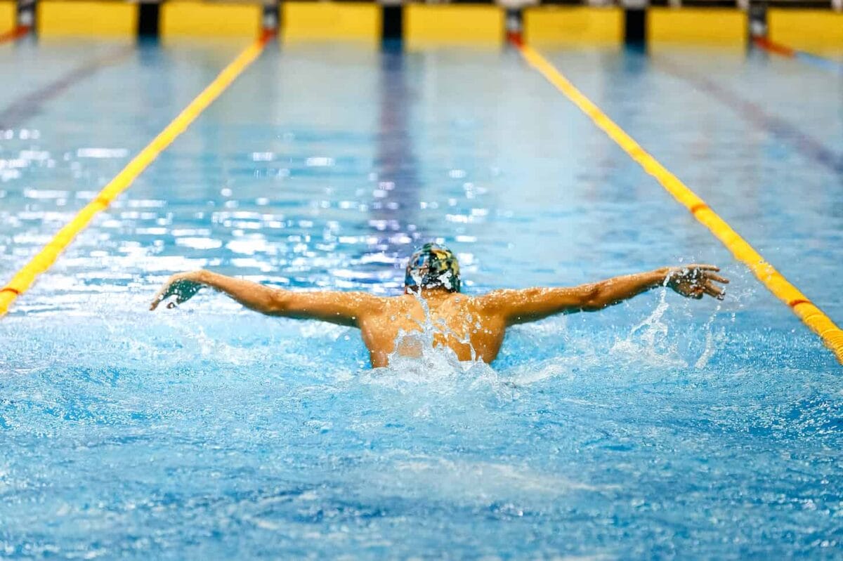 An image of one swimmer athlete swimming butterfly stroke in a pool track.